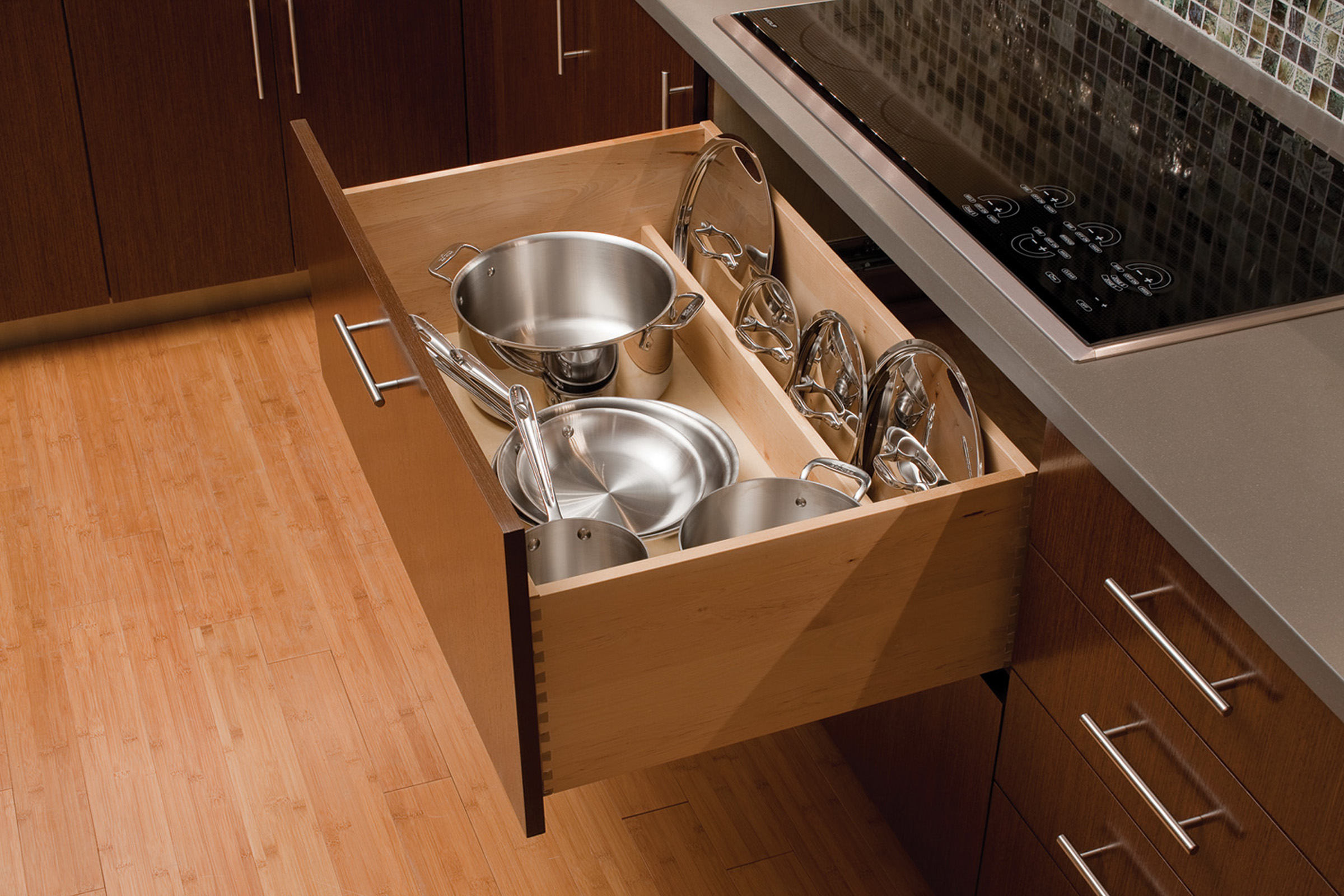 A Lid Storage Partition from Dura Supreme placed at the back of a wide, deep drawer neatly stores pot and pan lids to keep your pot and pan storage orderly and easy to access.